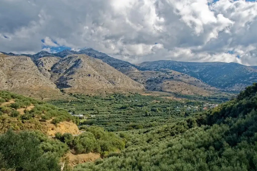 Expansive green plains stretching toward rugged mountains in the Heraklion region of Crete.