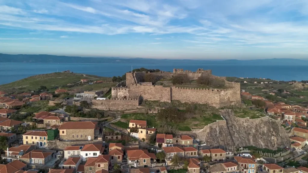 A wide view of the massive stone walls and towers of the Molyvos fortress on a hilltop.