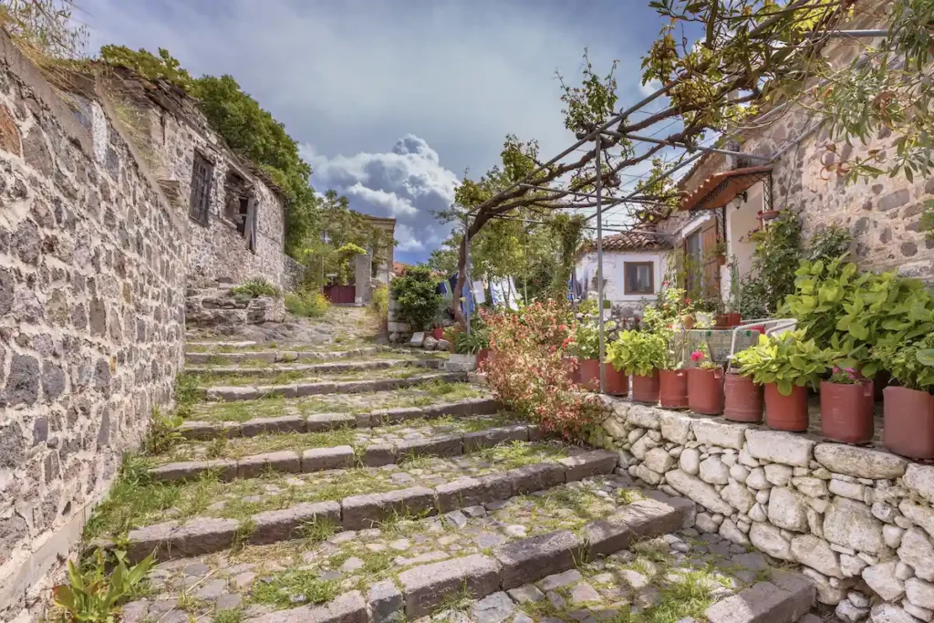 Steep stone stairs ascending between tall, traditional stone houses in a quiet neighborhood.