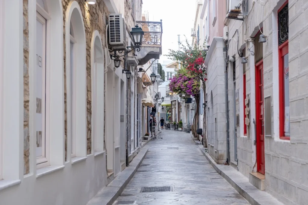 A narrow cobblestone street in central Ermoupoli, Syros, lined with historic tall buildings.