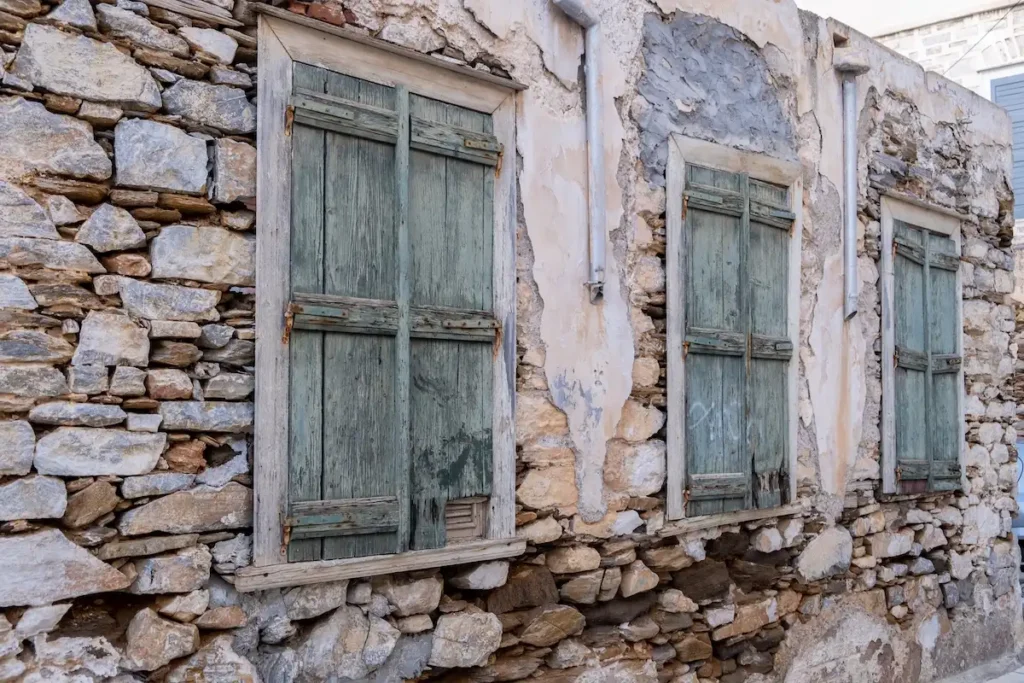 A weathered stone building facade in Ermoupoli with arched windows and stone details.