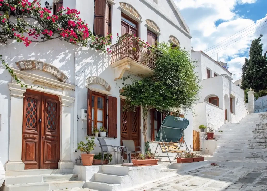 Traditional balconies in Pyrgos Tinos overflowing with jasmine and pink bougainvillea flowers.