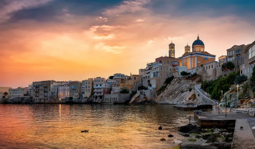 Neoclassical mansions of Vaporia district in Ermoupoli, Syros, with the blue dome of St. Nicholas Church overlooking the Aegean Sea.