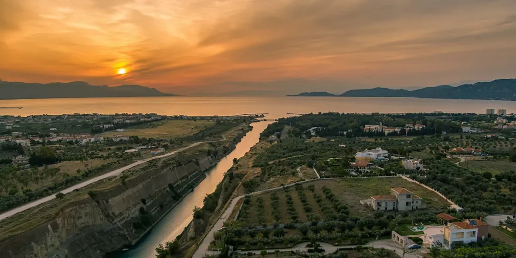 A majestic sunset view over the Corinthian Canal in Greece, highlighting luxury villas and the unique coastal landscape suitable for retirement investment.