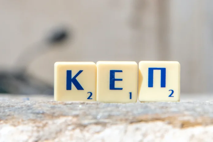 Scrabble greek letters spelling KEP placed in the foreground with a typical Greek island village in the background.