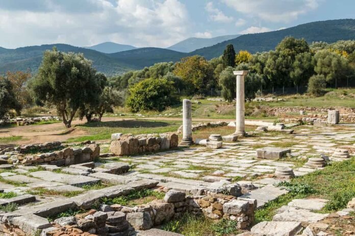 Two lone Doric columns of Ancient Messene standing tall against a blue sky, framed by the Mediterranean countryside.