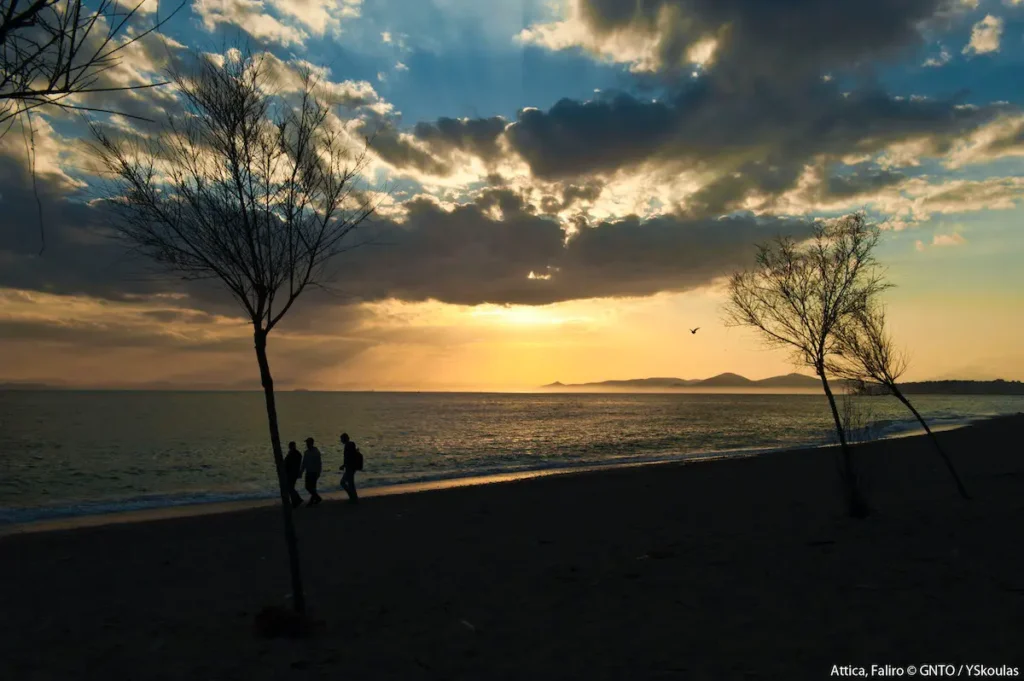 The sun setting over the Saronic Gulf, casting a golden light over the beach and the walking path in Palaio Faliro.