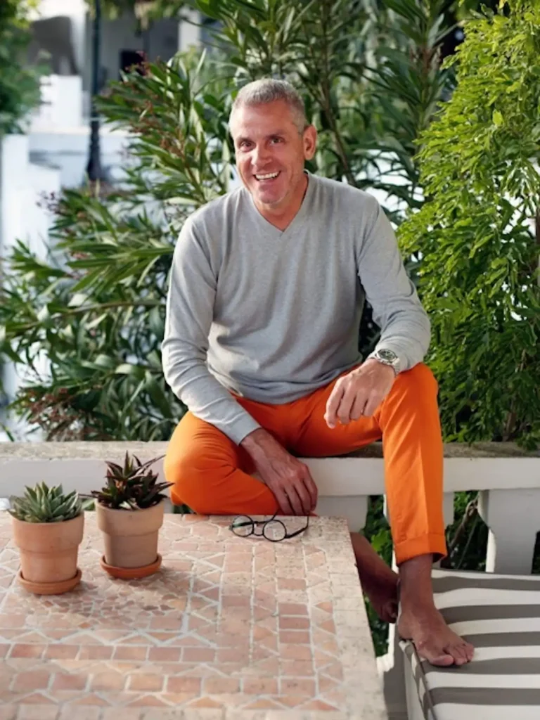 Designer George Efthimiou barefoot in orange pants on a Cycladic island.