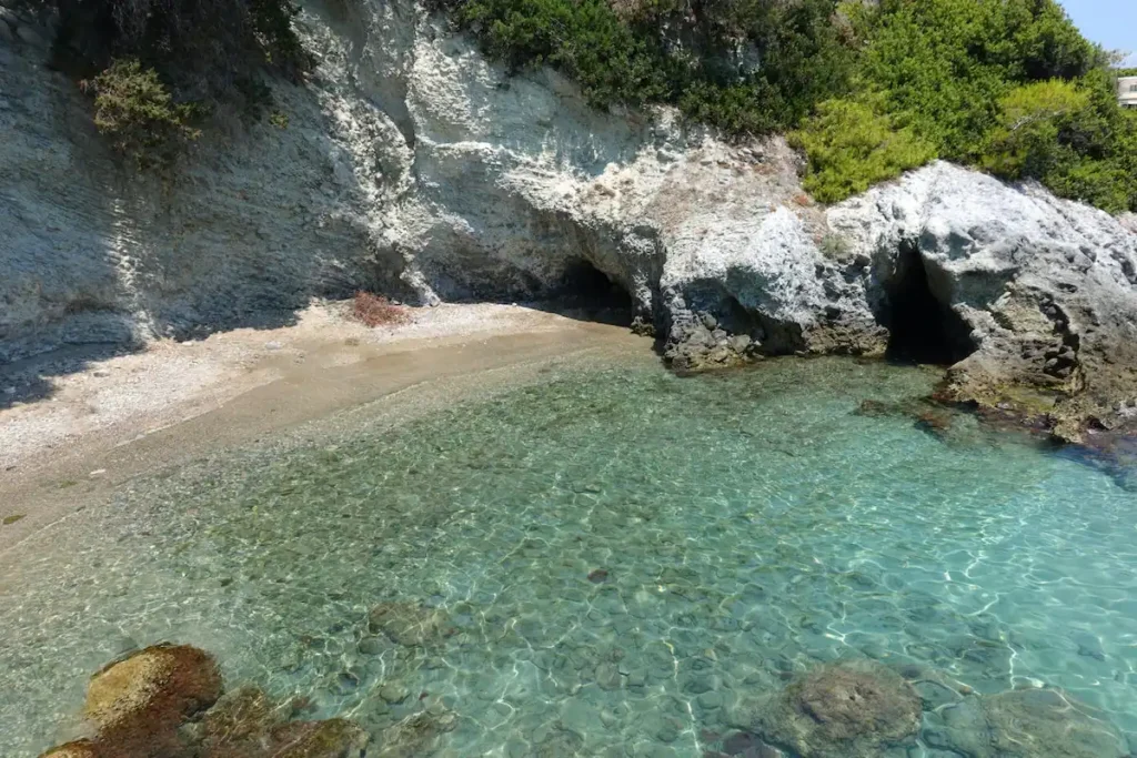 A small, secluded sandy cove in Aegina with calm turquoise water.