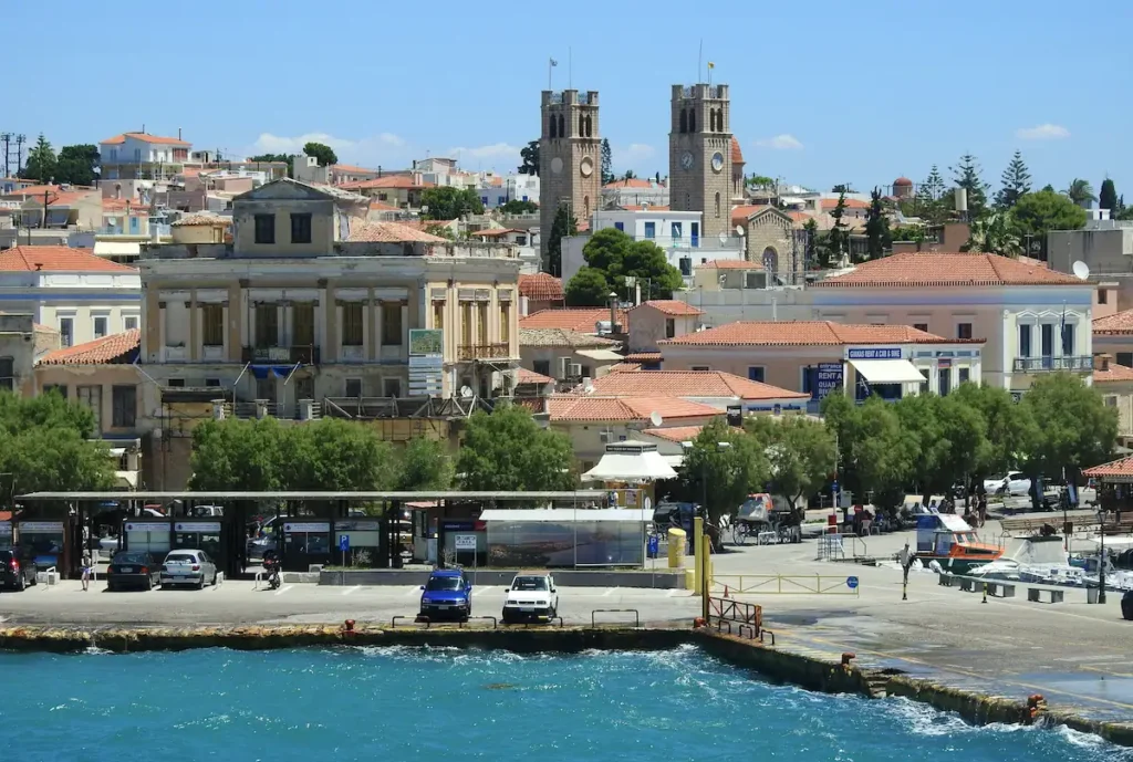 An aerial view of the Aegina Town port with ferries, yachts, and the waterfront promenade.