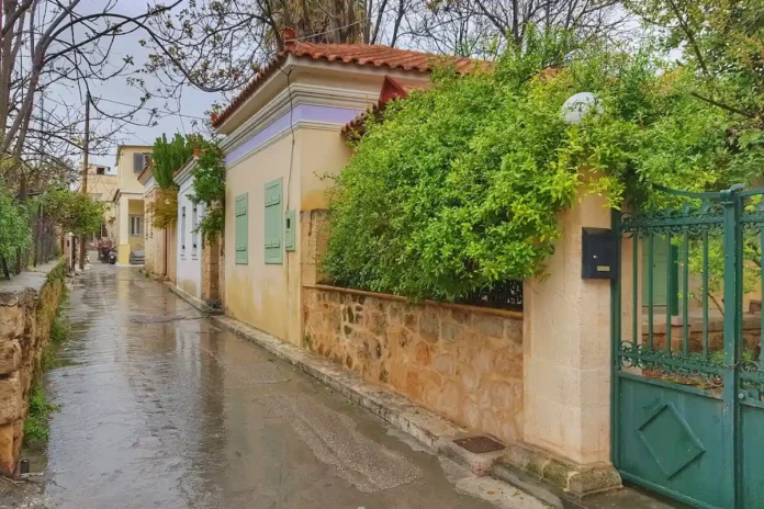 A neoclassical house on a quiet, wet cobblestone street.