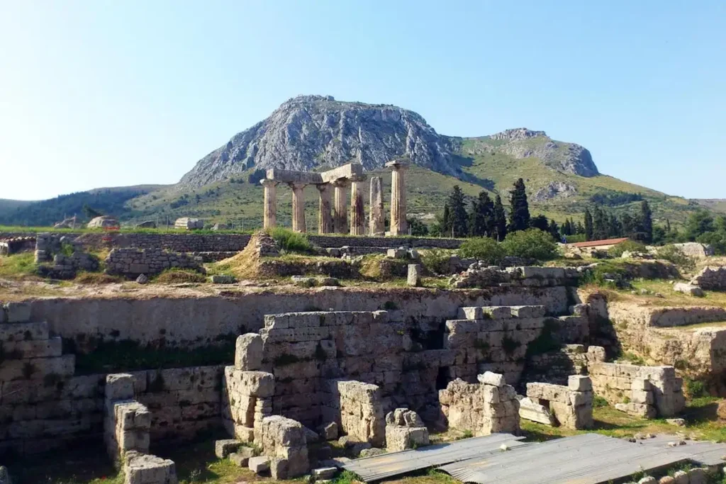 Close-up of the Doric Temple of Apollo columns in Ancient Corinth with the steep limestone massif of Akrokorinthos fortress in the background.