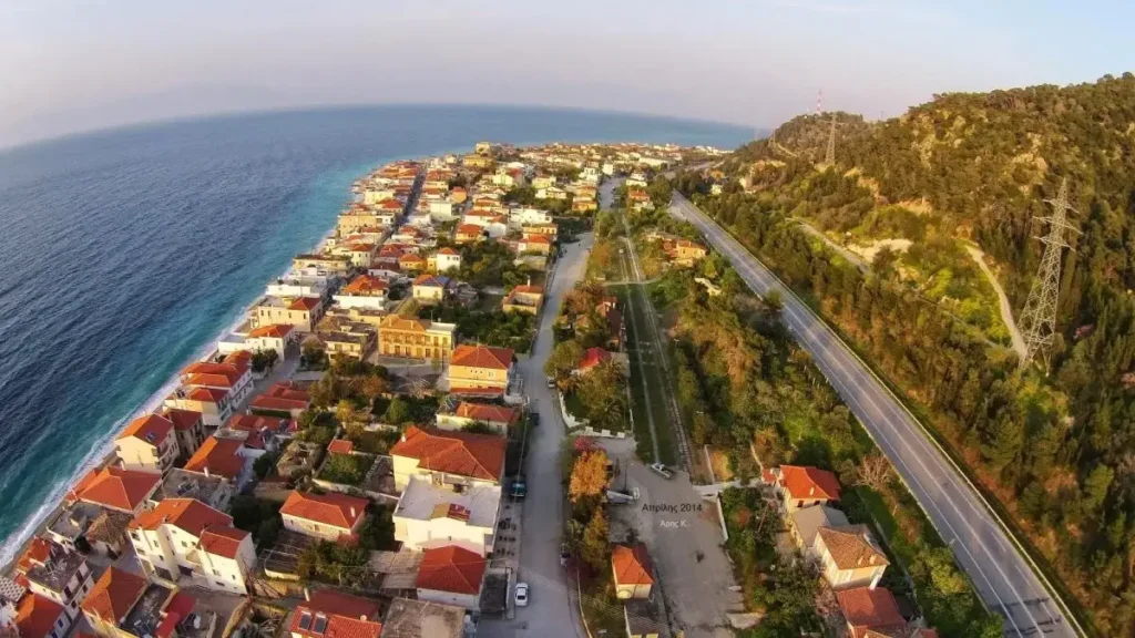 An aerial view of Derveni showing the seaside settlement and the Old National Road stretching toward the horizon.