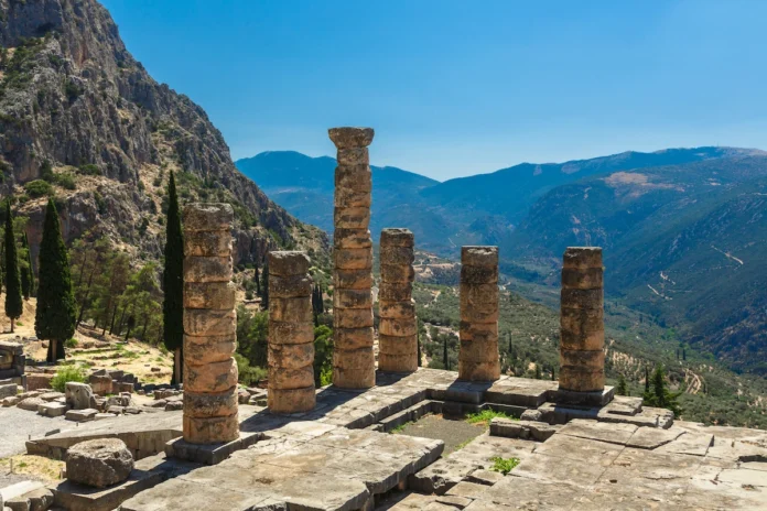 Six standing Doric columns of the Temple of Apollo at Delphi against the backdrop of Mount Parnassus.