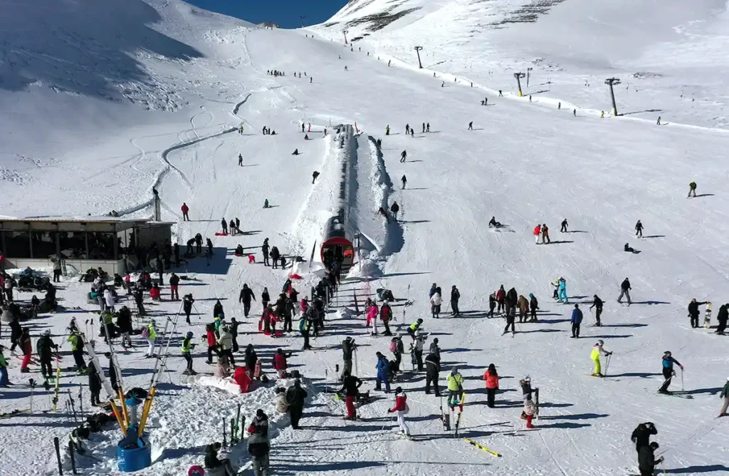 Panoramic view of the Velouchi Ski Center slopes covered in deep snow under a bright blue sky.