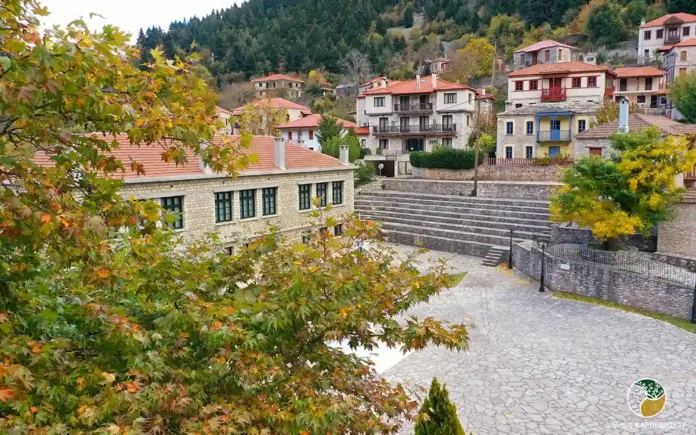 High-end traditional stone houses with red-tiled roofs set against a backdrop of majestic, jagged mountain peaks.
