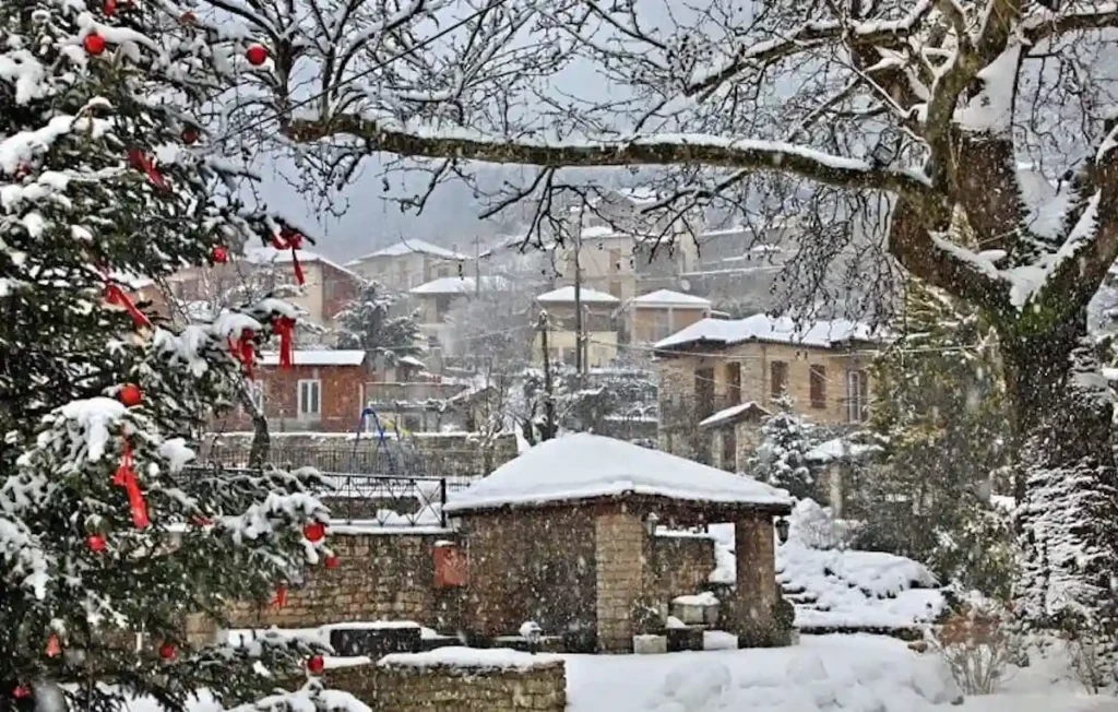 Koryshades village at Christmas with heavy snow on the stone roofs and warm lights in the windows.