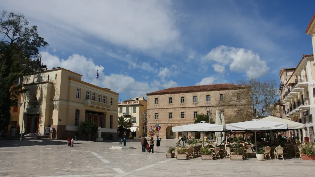 A large open public square paved with marble, surrounded by historic buildings and cafes.