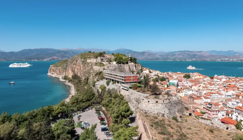 A wide panoramic view of Nafplio showing the red-tiled roofs and the sea in the background.