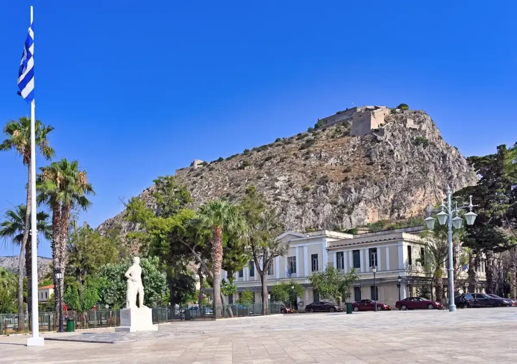View of Kapodistrias Square in Nafplio with the statue of Ioannis Kapodistrias and Palamidi Fortress in the background.