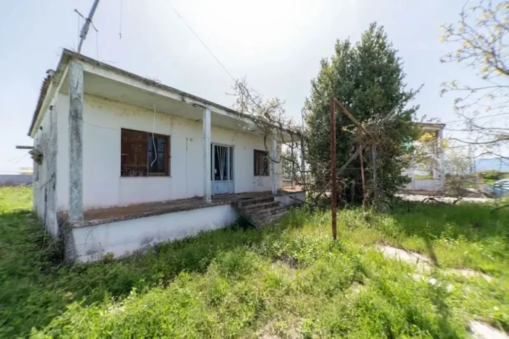 An older, single-story detached house near Keramoti requiring renovation, set on a large private plot of land.