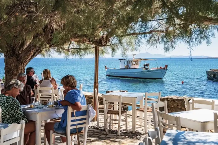 Retirees enjoying a seaside dinner at a traditional tavern in Naxos, Greece.