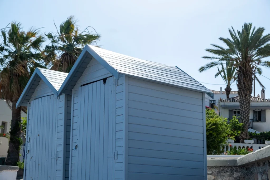 Small, traditional wooden changing huts on a pebbled beach in Spetses.