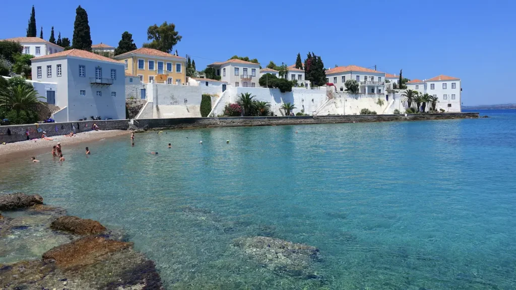 A row of historic, multi-story stone mansions directly facing the Saronic Gulf.