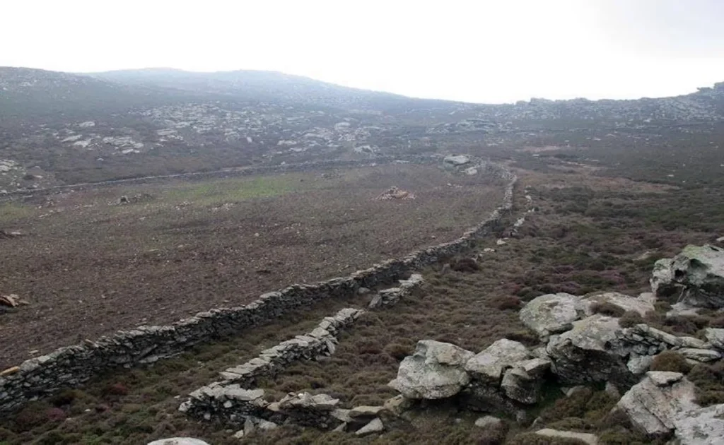 A wide traditional stone path lined with dry stone walls on Tinos island, originally designed for donkeys with baskets traveling between villages.