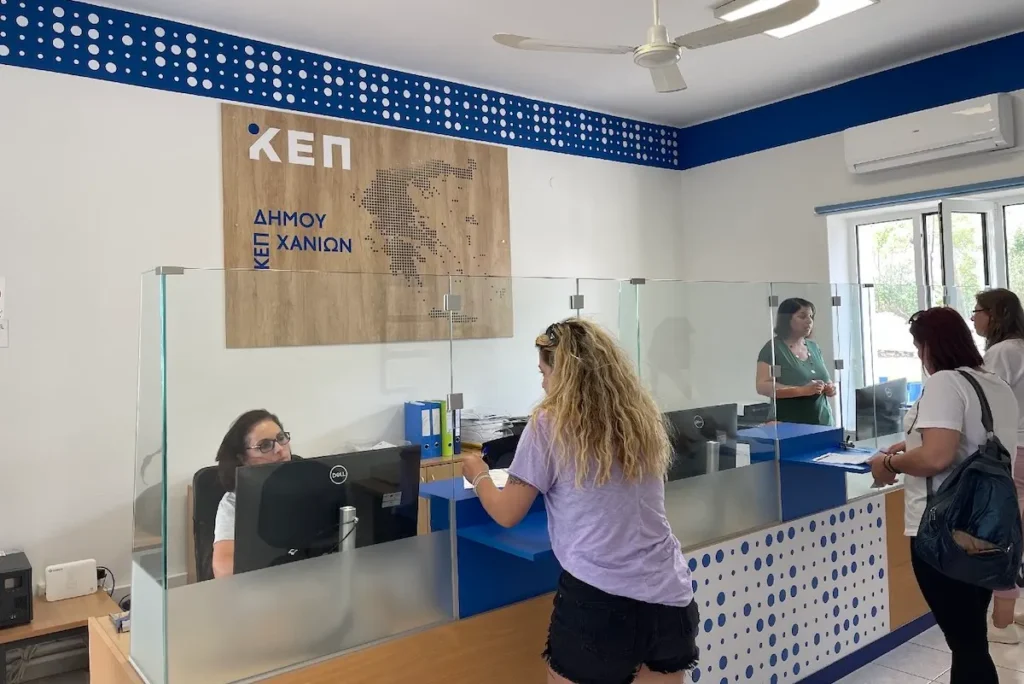 Citizens inside a KEP office with a visible Chania Municipality sign on the wall.
