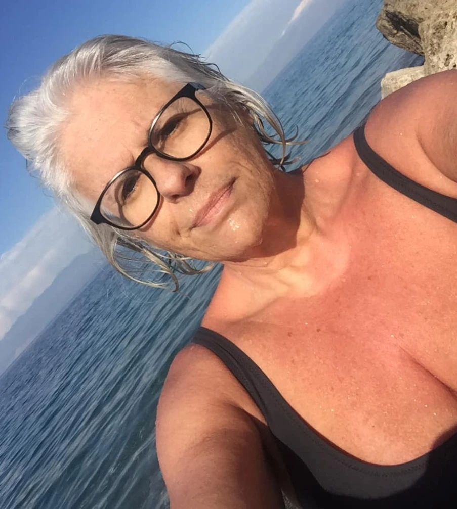 A woman swimming confidently in clear blue water during the winter season, representing a healthy Mediterranean lifestyle.