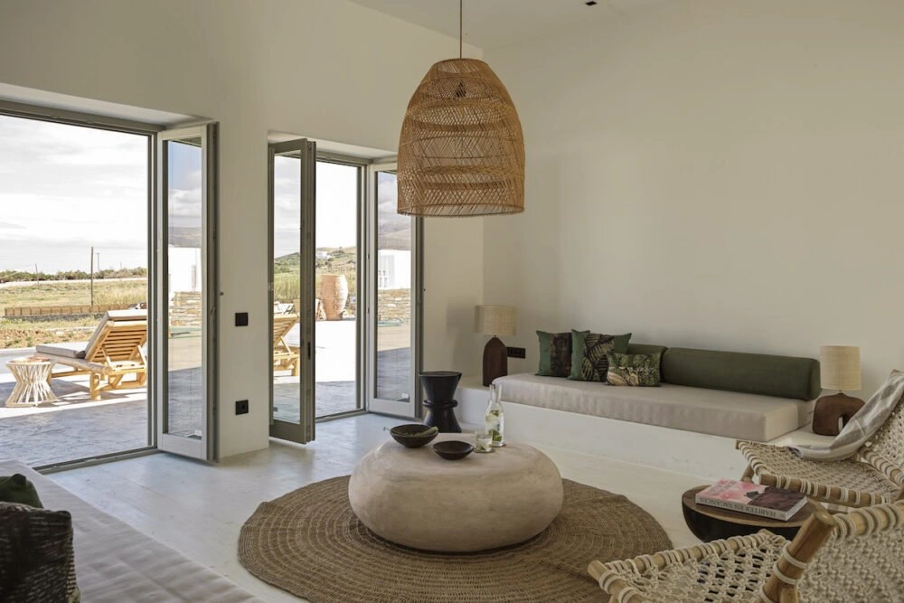 A modern minimalist living room in Antiparos, Greece, featuring a beige and white color palette with traditional Cycladic architectural elements.
