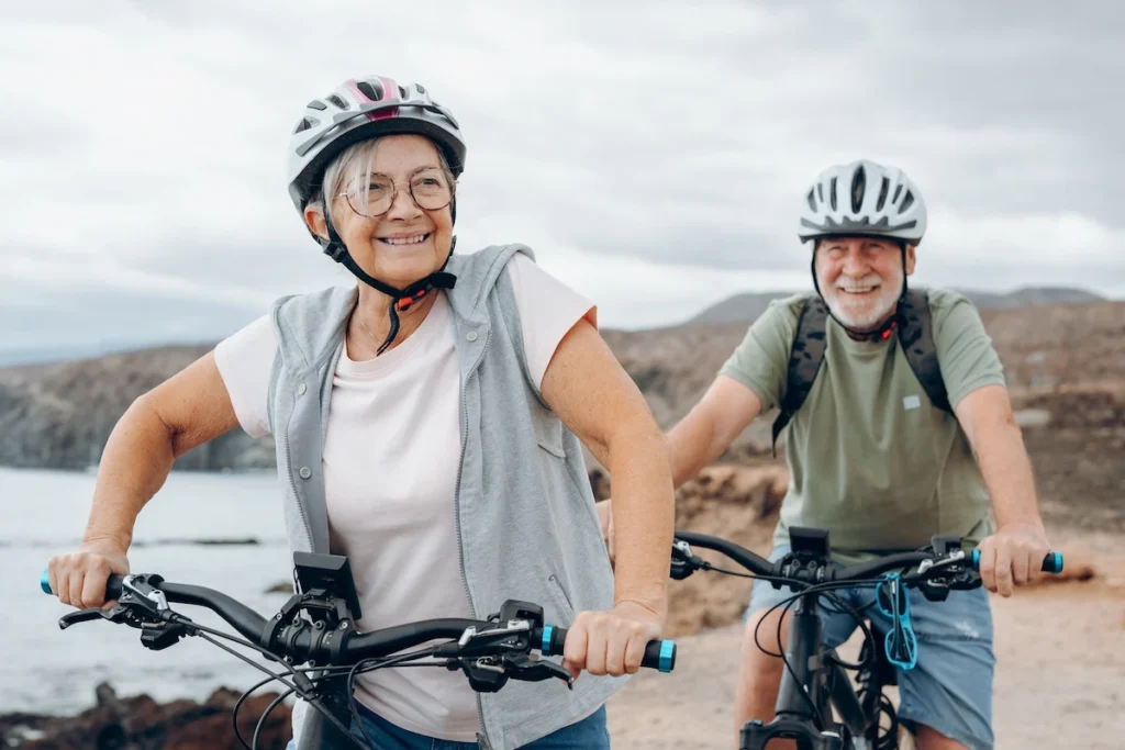 A candid shot of two people on bicycles riding along a dedicated, tree-lined bike path near the Kalamata waterfront.