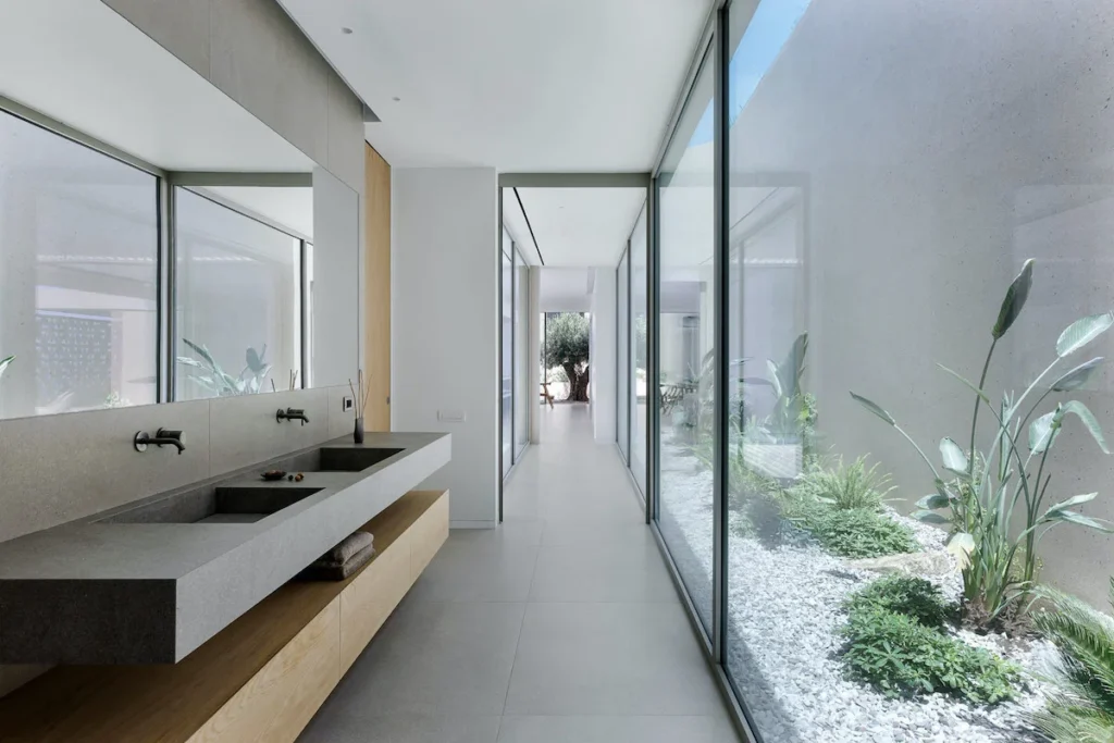 Interior garden and wide windows allow light to get in the modern bathroom.