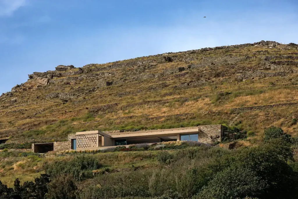 A panoramic view of the finished Slot House integrated into the Tinos landscape.