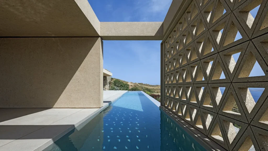 A modern infinity pool reflecting the Aegean horizon on a sunny day.