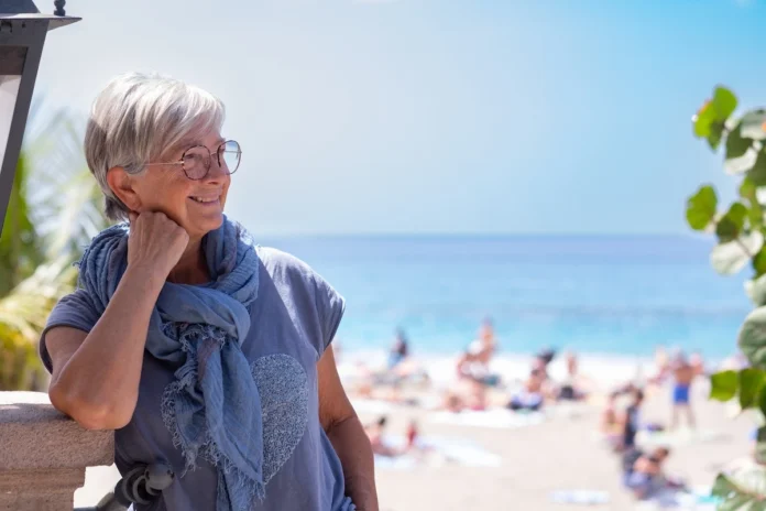 A woman standing thoughtfully by the shore, used as a conceptual illustration for a personal testimony about island life and social integration.