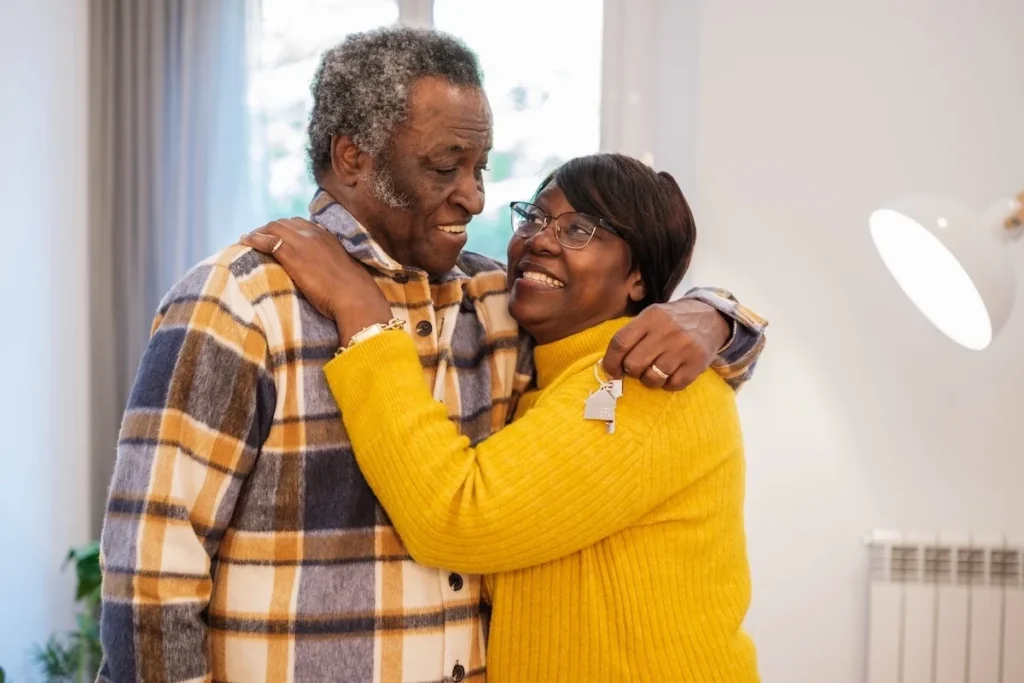 A generic photo-bank image featuring two models, a smiling adult couple, holding a generic house key and looking happily toward the future in their new home.
