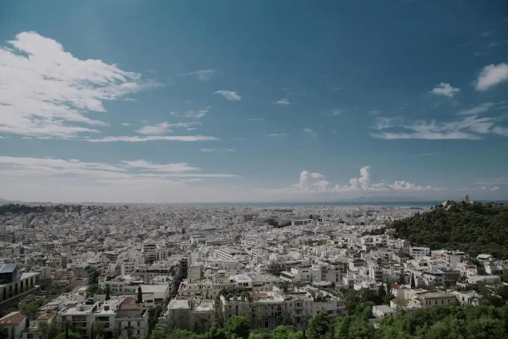 Panoramic view of the Athens city basin extending to the Saronic Gulf, illustrating the scale of the real estate market.