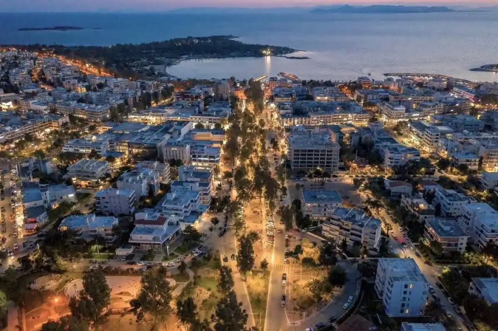 Aerial night view of Glyfada on the Athens Riviera, showing illuminated streets, seaside avenues, restaurants, shops and the vibrant coastal neighbourhood popular with international residents and retirees.