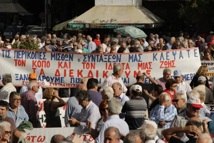 Retirees at a protest rally in central Athens holding banners in Greek, demonstrating against pension cuts and high living costs.