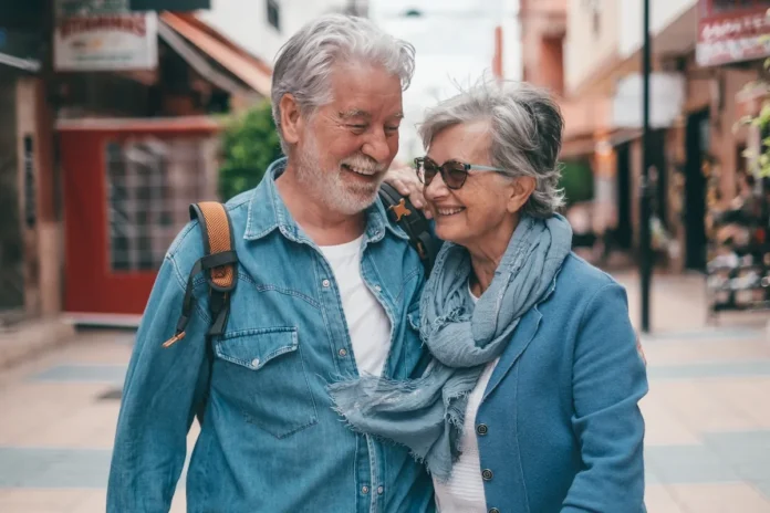 A joyful couple laughing together while walking down a sunlit city street, conveying a sense of freedom and financial ease.