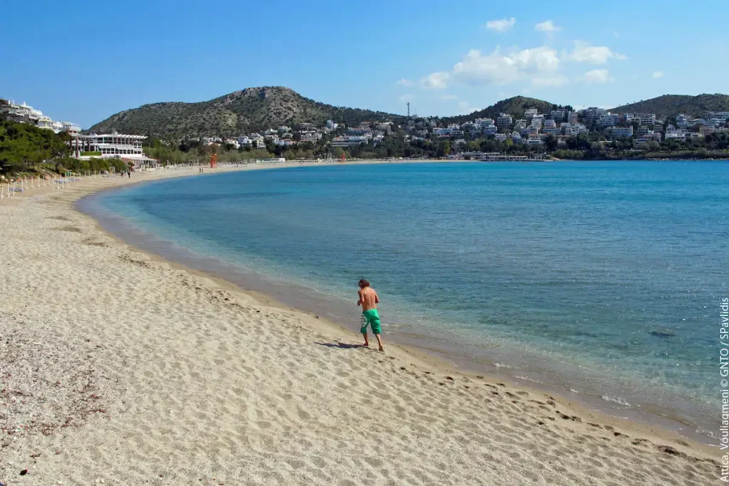 A solitary man jogging along the shoreline of a long, golden sand beach during the quiet off-season.