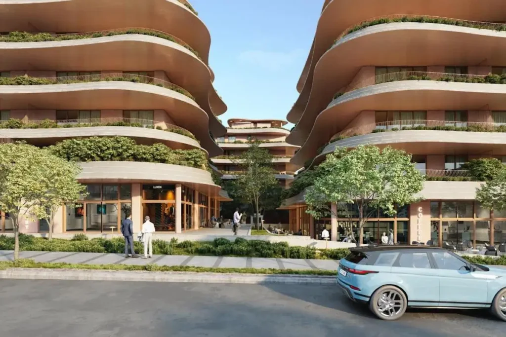 A pristine digital architectural rendering of the planned Little Athens residential neighborhood at the Ellinikon development, showing idealized modern apartment buildings, manicured green pathways, and flawless clear blue skies.