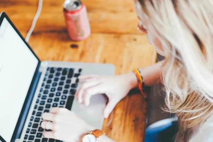 A blonde woman working at a laptop at an office desk.