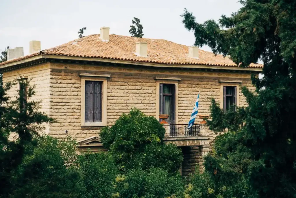 A traditional Greek stone house flying the Greek flag, representing property ownership in Greece and its distinct tax treatment under the local rental income rules.
