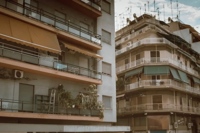 A dense cluster of 1970s Athenian apartment buildings with faded green and orange fabric balconies and a skyline crowded with metal TV antennas.