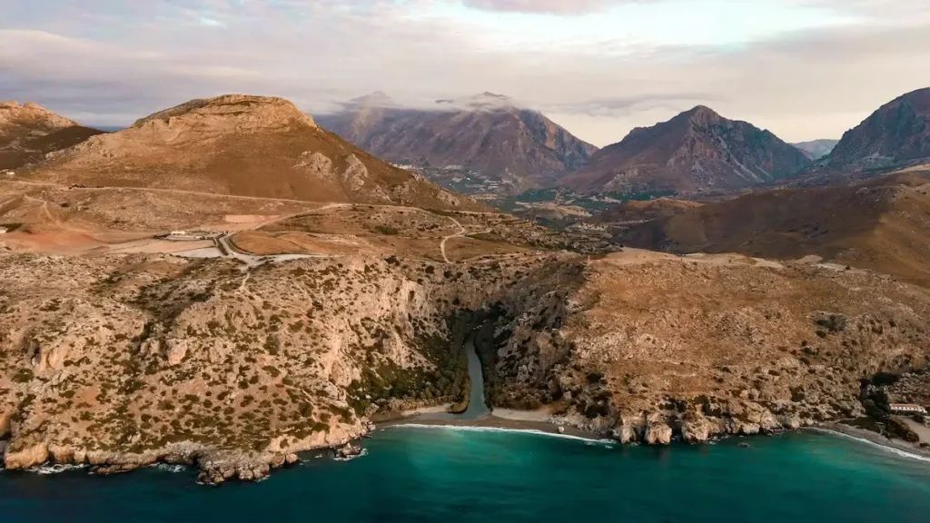 Golden sunrise illuminating the palm forest and coastline of Preveli Beach in Crete.
