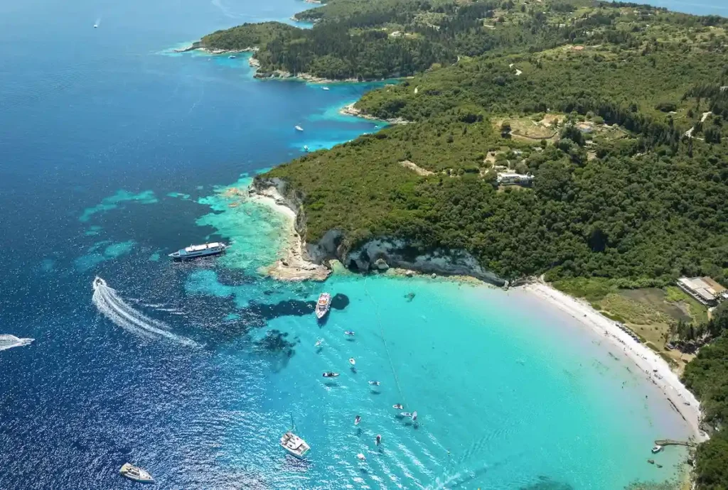 Aerial view of a secluded white-sand beach and vibrant turquoise water on Paxos Island, Greece.