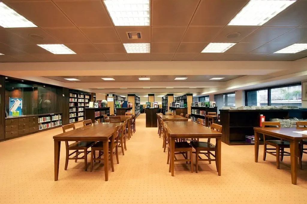 An empty, modern library and study space at the Hellenic American Union with bookshelves, quiet work desks, and study materials.